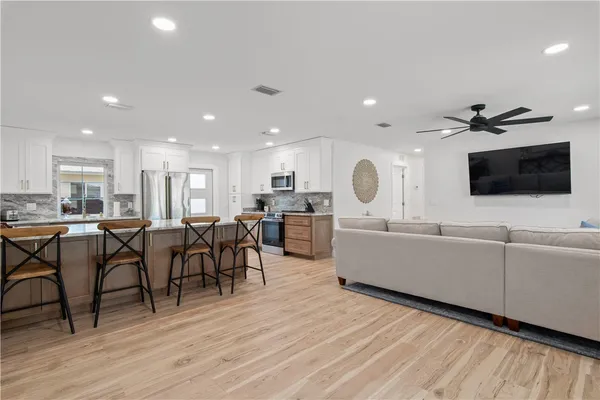 a living room with furniture a flat screen tv and kitchen view