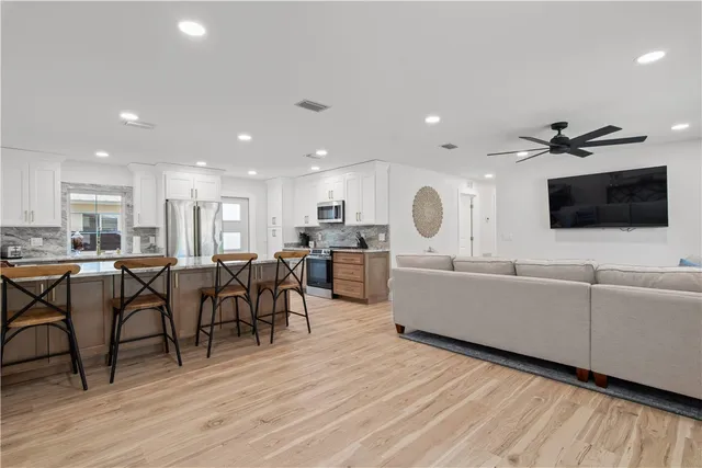 a living room with furniture a flat screen tv and kitchen view