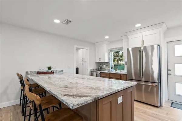 a kitchen with granite countertop kitchen island a refrigerator a counter and wooden cabinets