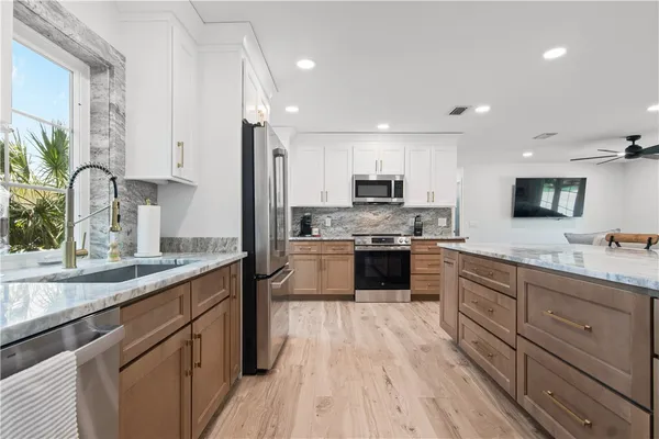 a large kitchen with stainless steel appliances granite countertop a lot of counter space and wooden floors