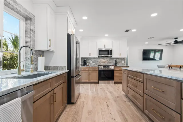 a large kitchen with stainless steel appliances granite countertop a lot of counter space and wooden floors