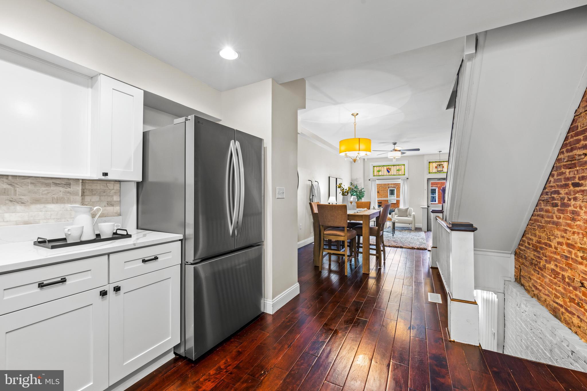 1243 Hull Street Baltimore, MD 21230 - Photo 16 of 39 a kitchen with stainless steel appliances a refrigerator a stove a sink dishwasher and a dining table with wooden floor