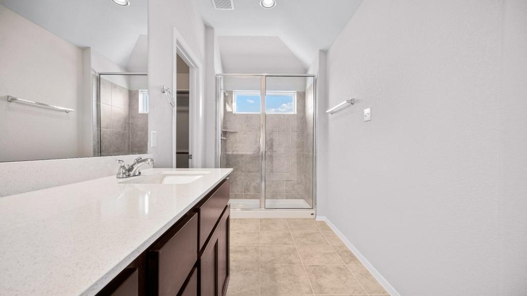 208 Stein Road Georgetown, TX 78626 - Photo 23 of 30 Bathroom with a stall shower, vanity, lofted ceiling, a walk in closet, and tile patterned flooring