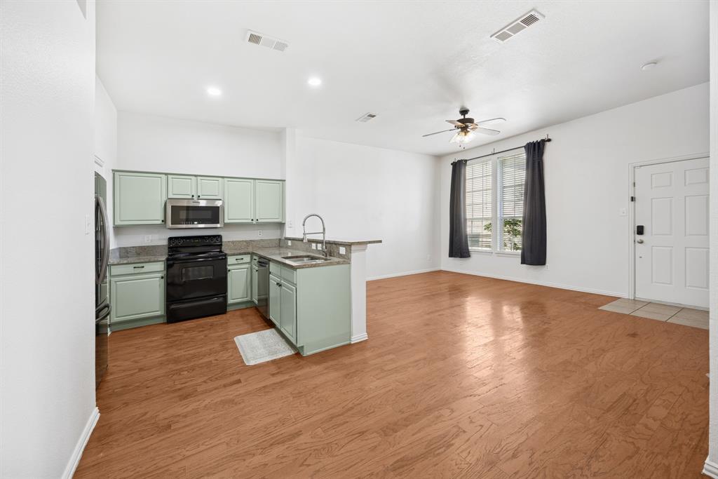 1747 Preston On The Lake Boulevard Little Elm, TX 75068 - Photo 13 of 23 a kitchen with stainless steel appliances a stove top oven a sink dishwasher and a refrigerator with wooden floor