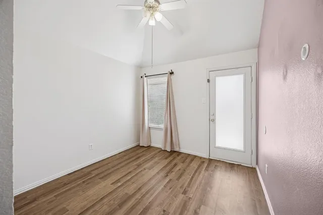 an empty room with wooden floor and ceiling fan