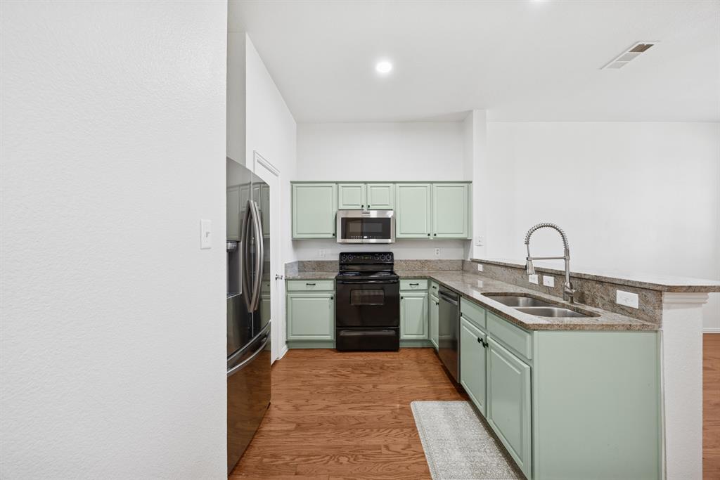 1747 Preston On The Lake Boulevard Little Elm, TX 75068 - Photo 8 of 23 a kitchen with stainless steel appliances granite countertop a sink and a stove