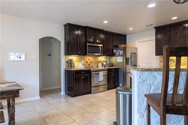 a kitchen with stainless steel appliances granite countertop a refrigerator and a stove top oven