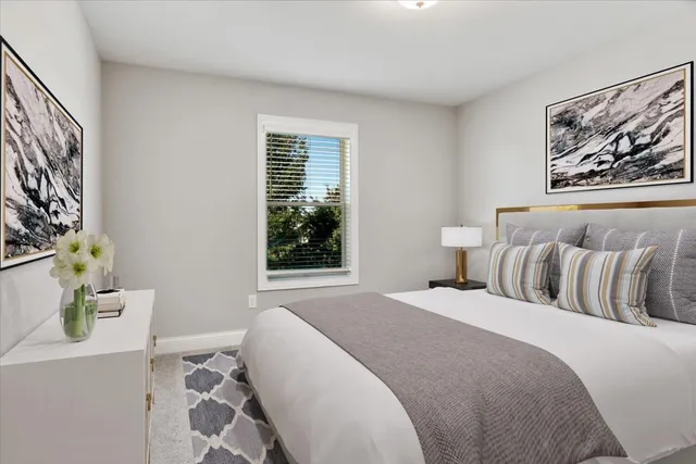 a bedroom with a bed and a window with painting on the wall