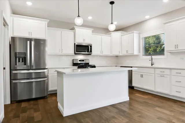 a kitchen with kitchen island white cabinets and stainless steel appliances