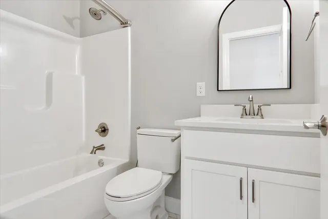 a bathroom with a toilet sink vanity tub and mirror
