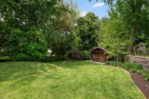 a blue house with a big yard and large trees