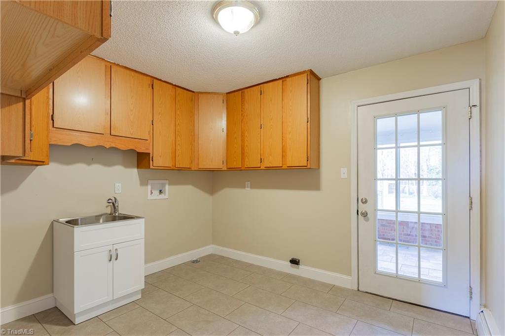 5104 Mockingbird Road Greensboro, NC 27406 - Photo 12 of 25 The NEW tile floor extends to the very large Mudroom/ Laundry Room, featuring a NEW utility sink and ample cabinets! This room creates easy access from the giant Carport!