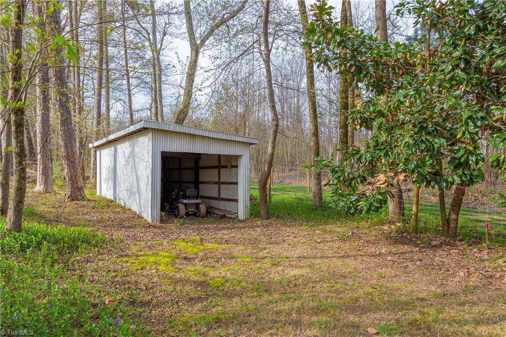 5104 Mockingbird Road Greensboro, NC 27406 - Photo 21 of 25 Near the rear of the lot you'll find your approx. 10x24 pole shed, featuring a clever sloping roof and full siding!
