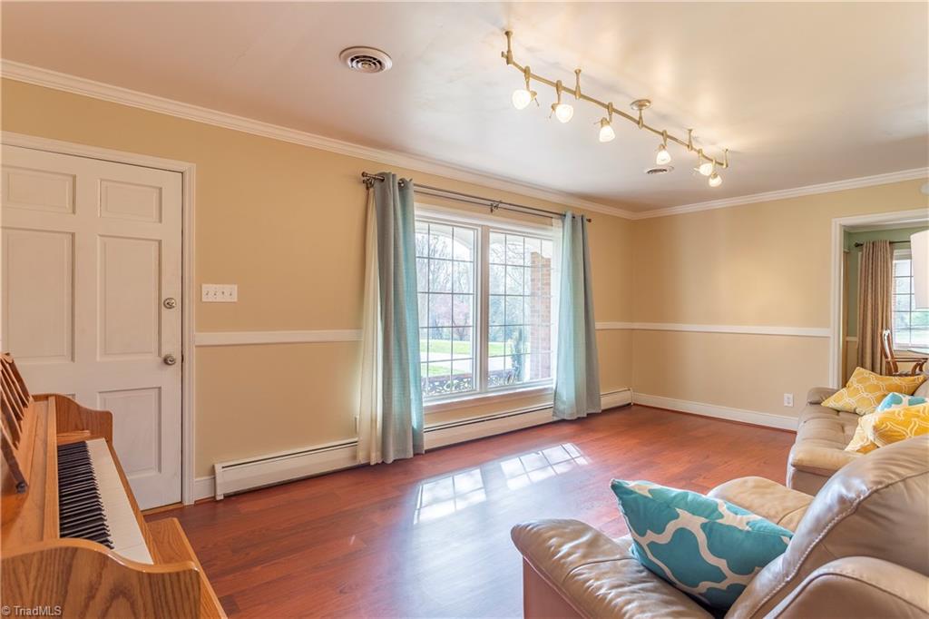 The beautiful front Living Room features a large bright window, upscale new lighting, chair rail & crown!