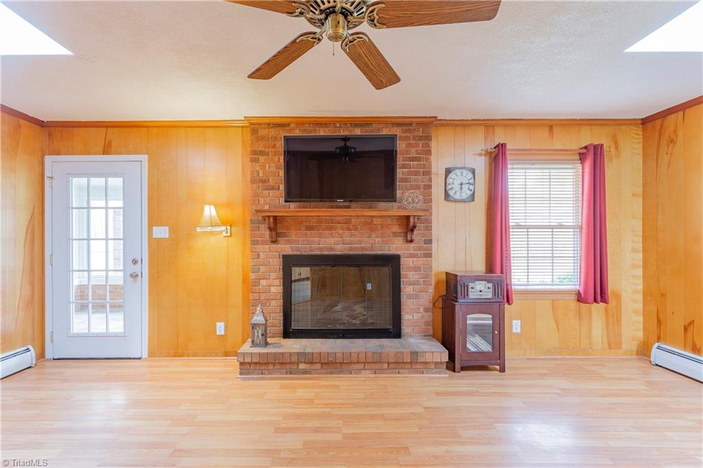 The back Den leads to the magnificent Sunroom beyond, and features this gorgeous brick fireplace with wood mantle! 