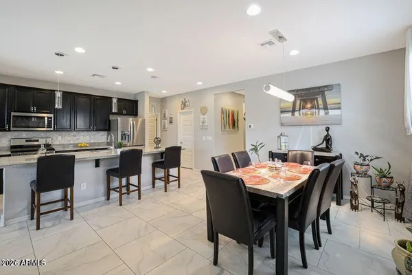 a open dining room with stainless steel appliances kitchen island granite countertop a dining table chairs and a refrigerator