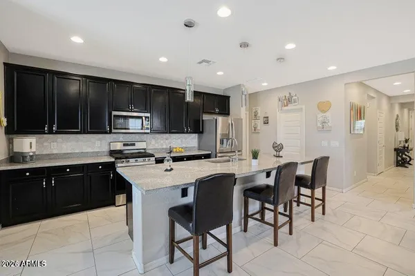 a kitchen with kitchen island granite countertop a sink a stove a counter top space and cabinets