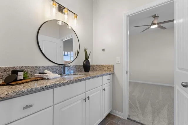 a bathroom with a granite countertop double vanity sink and a mirror