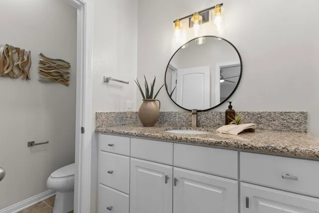 a bathroom with a granite countertop toilet sink and mirror
