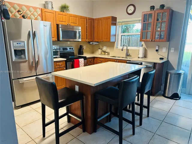 a kitchen with stainless steel appliances granite countertop a dining table chairs cabinets a sink and a refrigerator