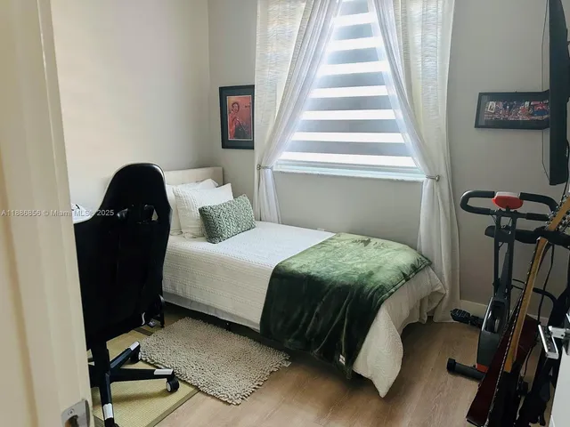 a bedroom with a bed window and a flat screen tv