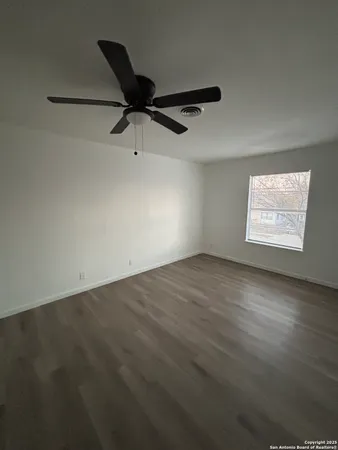 an empty room with windows and fan