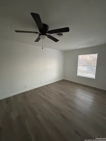an empty room with windows and fan