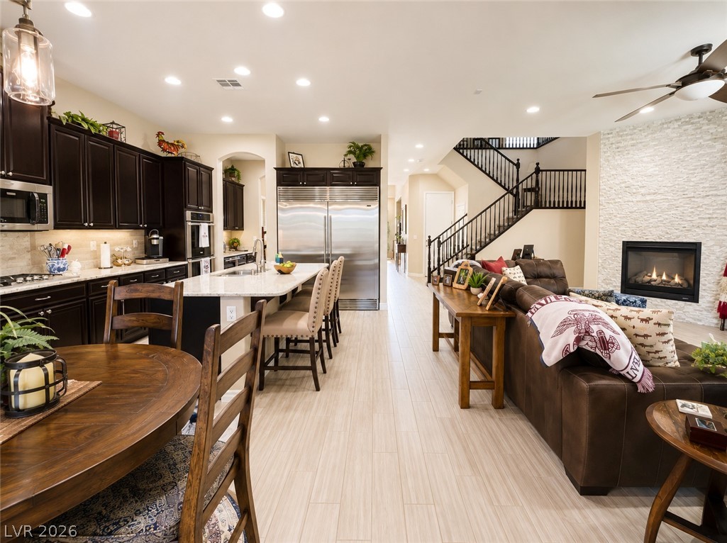 9724 University Ridge Avenue Las Vegas, NV 89149 - Photo 61 of 61 An open floorplan seamlessly connects the kitchen to the living room, featuring a fireplace and staircase.