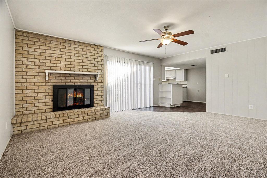 6532 Blue Ridge Trail Plano, TX 75023 - Photo 9 of 25 a view of an empty room with a fireplace and a ceiling fan