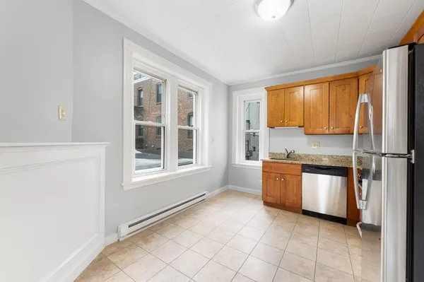 a large white kitchen with granite countertop a refrigerator and a sink