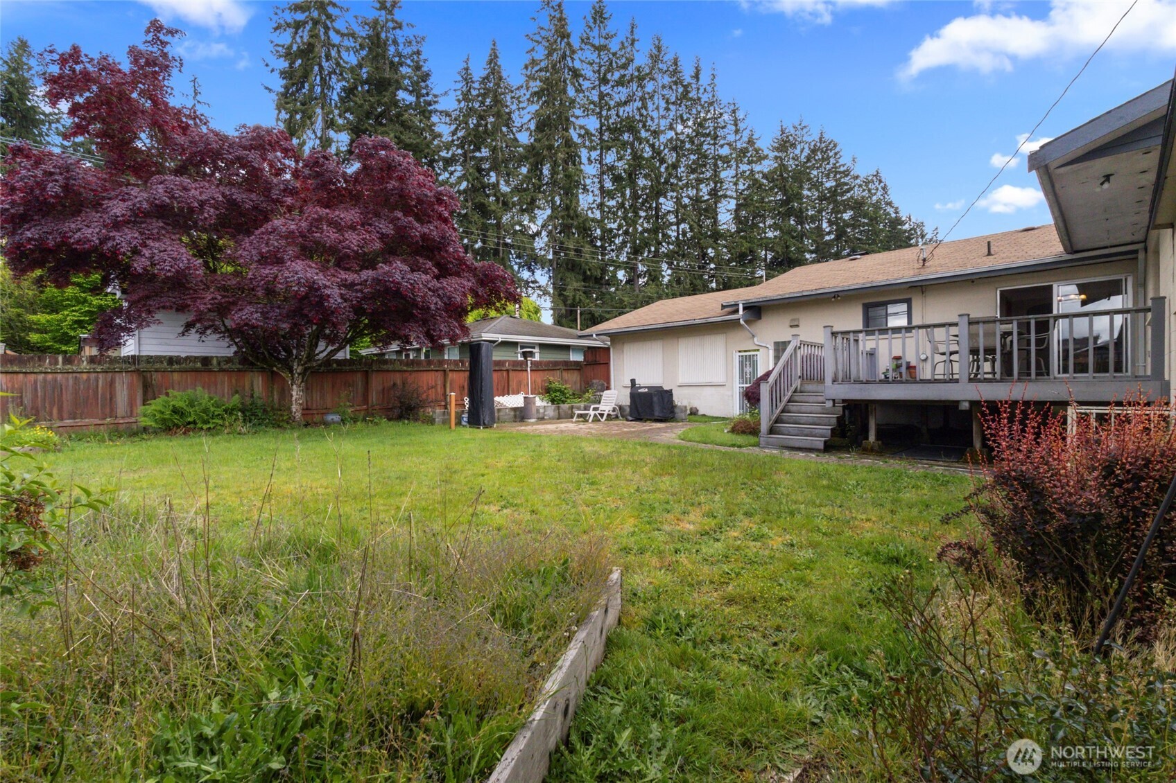 5117 Delaware Avenue Everett, WA 98203 - Photo 25 of 36 a backyard of a house with wooden fence and large trees