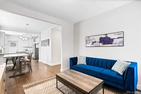 a living room with furniture a refrigerator and kitchen view