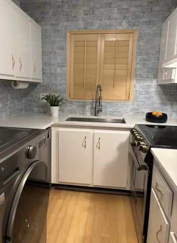 a kitchen with granite countertop a sink a stove and cabinets
