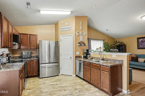 a kitchen with stainless steel appliances granite countertop a refrigerator a stove and a sink