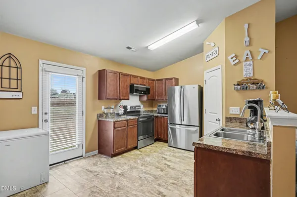 a kitchen with stainless steel appliances granite countertop a refrigerator a stove and a sink with wooden floor