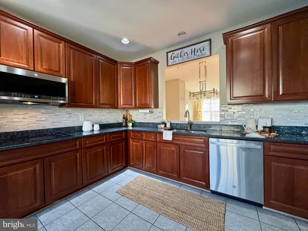 a kitchen with stainless steel appliances granite countertop wooden cabinets a stove top oven a sink and dishwasher