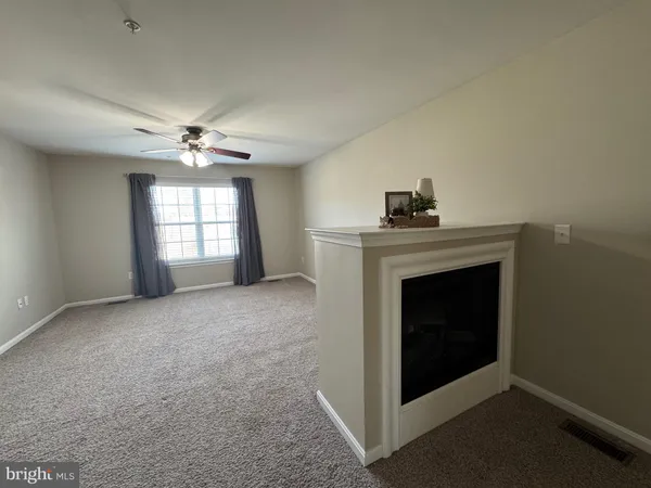 a view of an empty room with a fireplace and a window