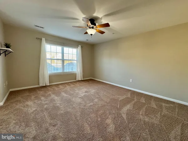 an empty room with windows and ceiling fan