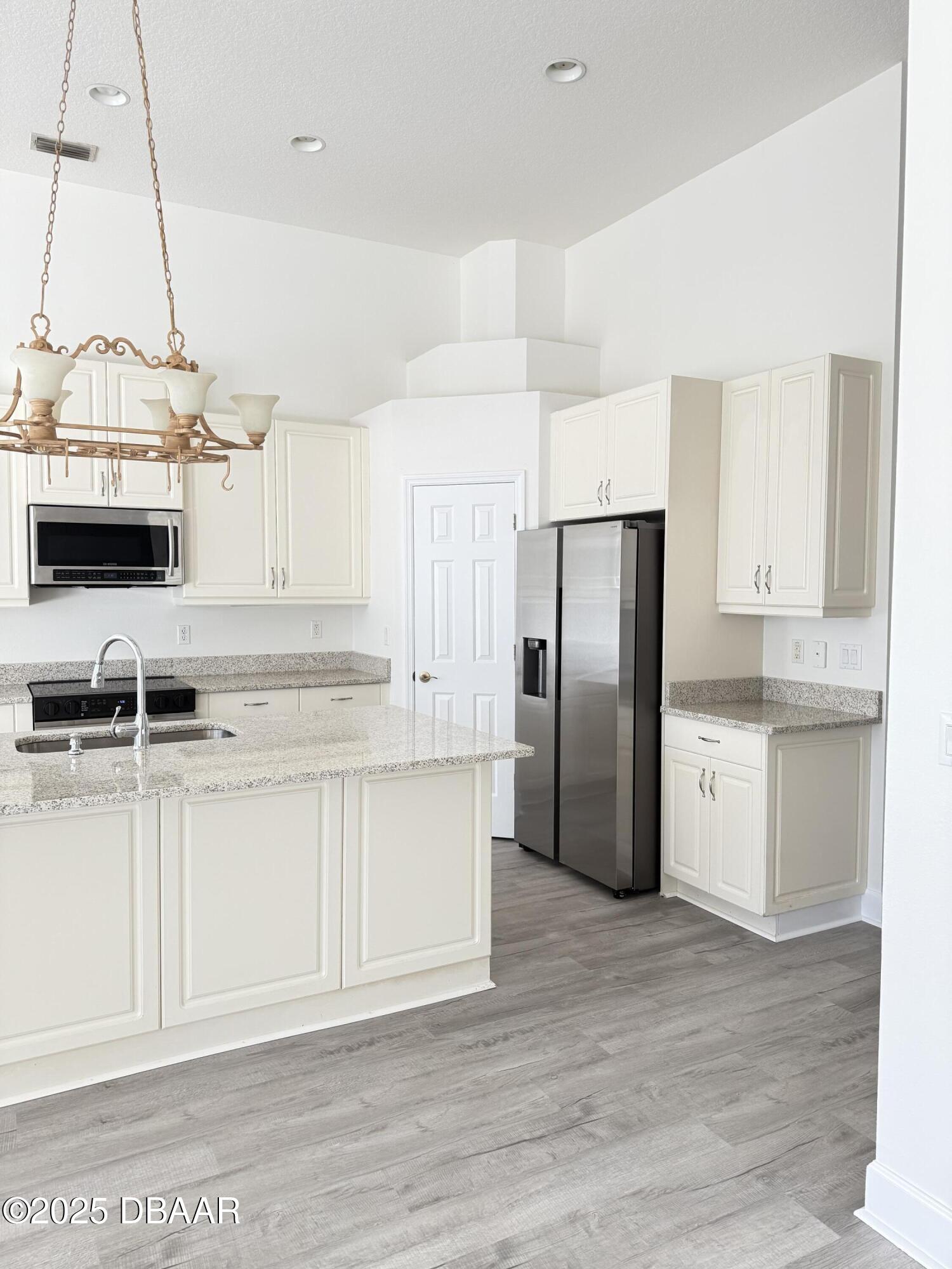 14 Deep Woods Way Ormond Beach, FL 32174 - Photo 17 of 38 a kitchen with stainless steel appliances granite countertop a refrigerator a sink dishwasher a stove and white cabinets with wooden floor