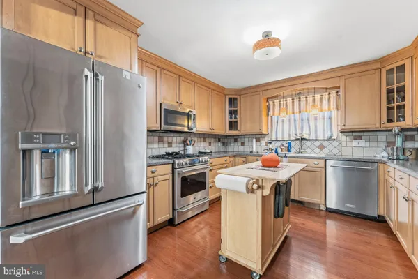 a kitchen with stainless steel appliances granite countertop a stove a sink dishwasher a refrigerator and a microwave oven with wooden floor