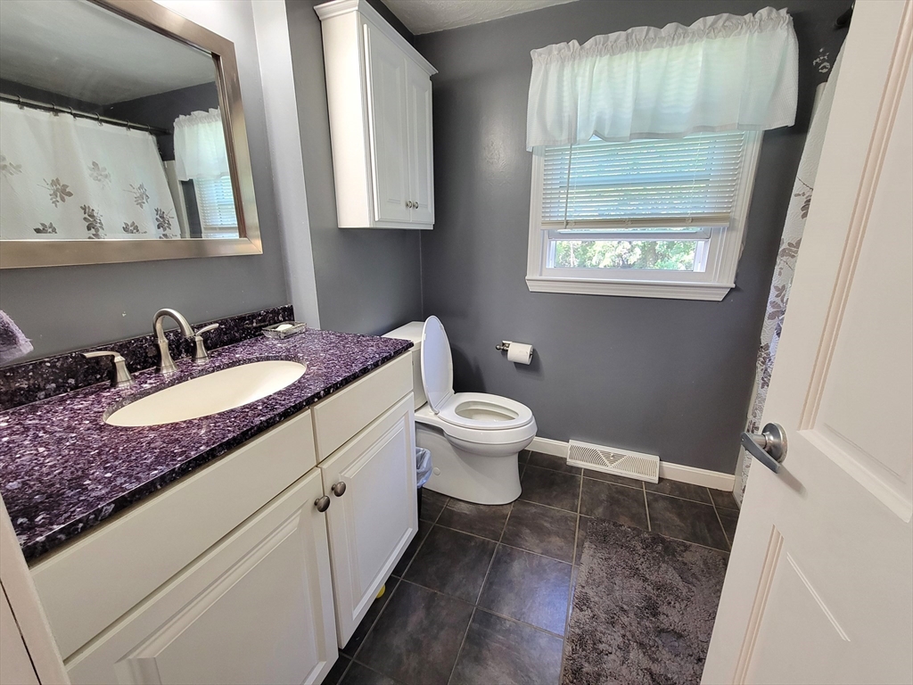 75 Brown Street Tewksbury, MA 01876 - Photo 16 of 28 a bathroom with a granite countertop sink a toilet and a mirror