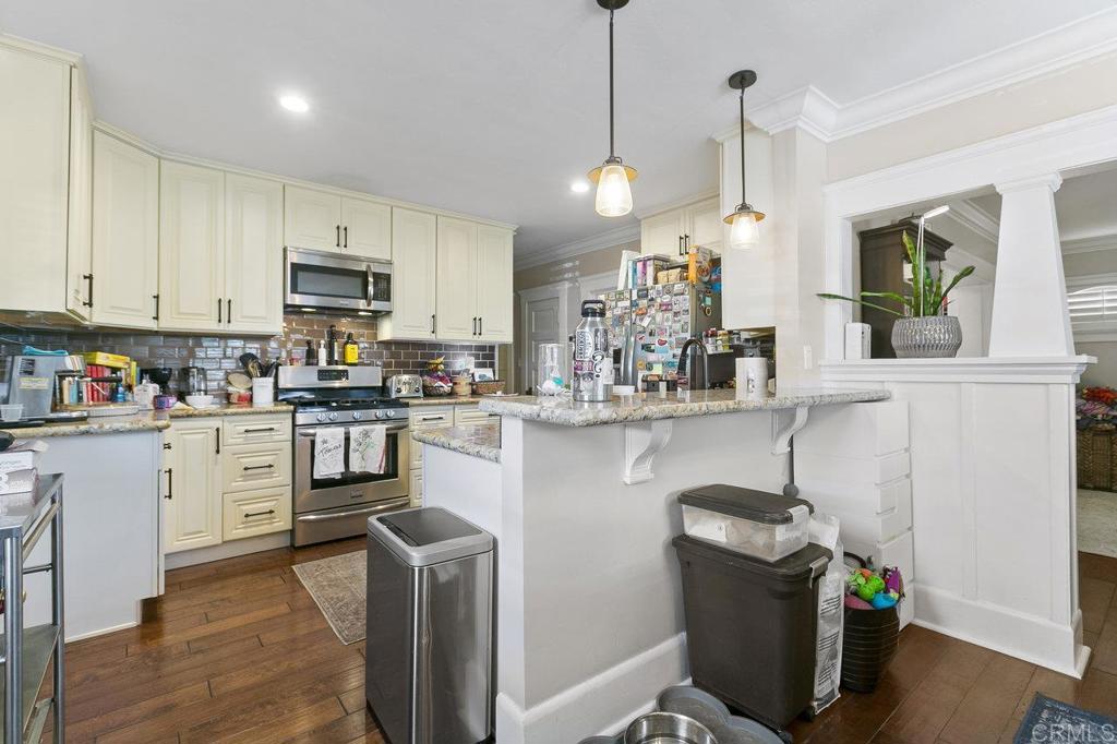 3373-3379 1/2 Herman Avenue San Diego, CA 92104 - Photo 16 of 70 a kitchen with stainless steel appliances granite countertop a refrigerator a sink dishwasher a stove and a dining table with wooden floor