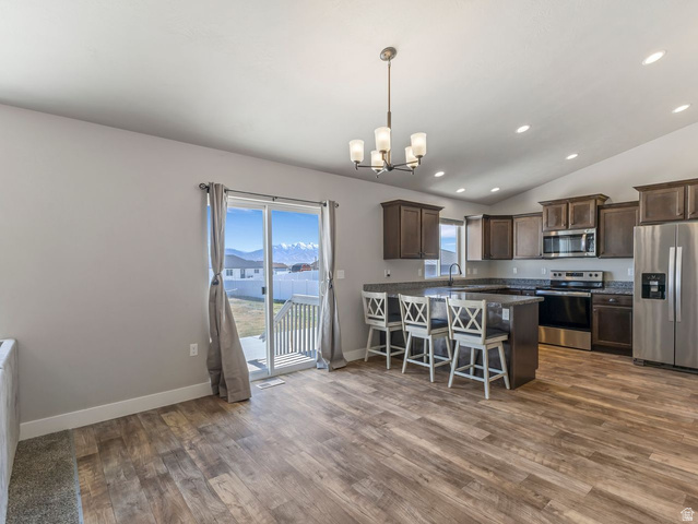 573 South Maxwell Drive Grantsville, UT 84029 - Photo 7 of 25 Kitchen with a peninsula, stainless steel appliances, a kitchen breakfast bar, dark wood finish cabinets, and suspended lighting