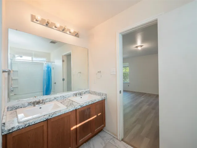 a bathroom with a granite countertop double vanity sink and mirror