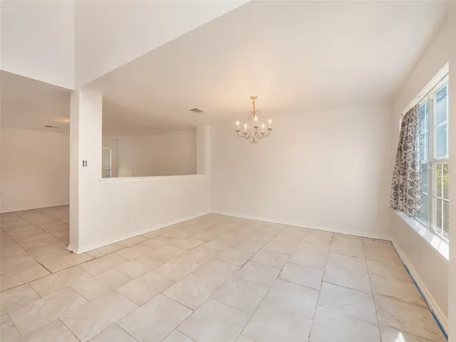 an empty room with chandelier fan and windows
