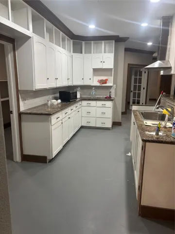 a kitchen that has a lot of cabinets in it and wooden floors
