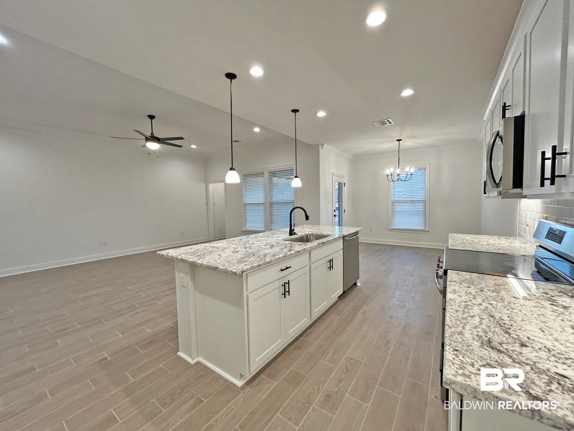 1744 Breckinridge Place Foley, AL 36535 - Photo 5 of 26 Kitchen featuring white cabinets, a chandelier, an island with sink, light stone countertops, and stainless steel appliances