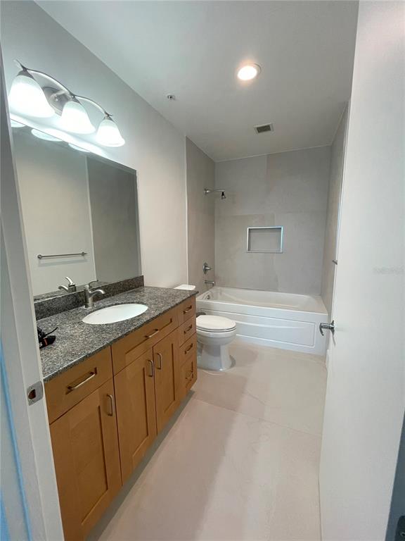 150 East Robinson Street, Unit 2A6 Orlando, FL 32801 - Photo 16 of 33 a bathroom with a granite countertop sink a toilet a large mirror and bathtub