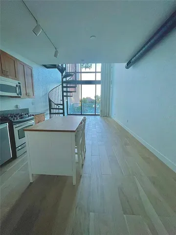 a kitchen with stainless steel appliances granite countertop a table chairs sink and cabinets