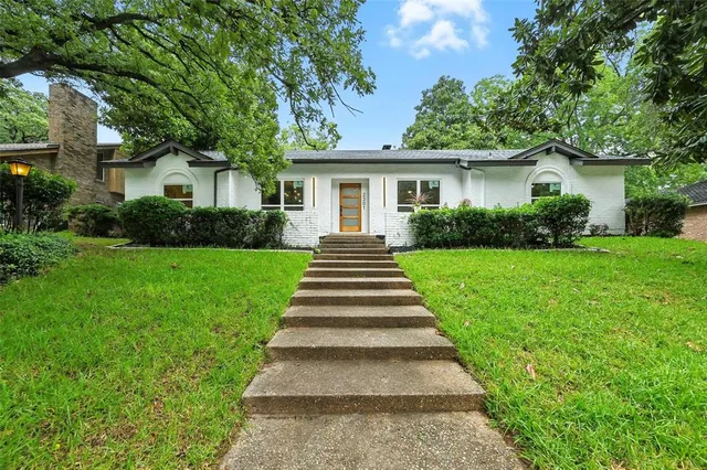 a front view of a house with a yard and potted plants